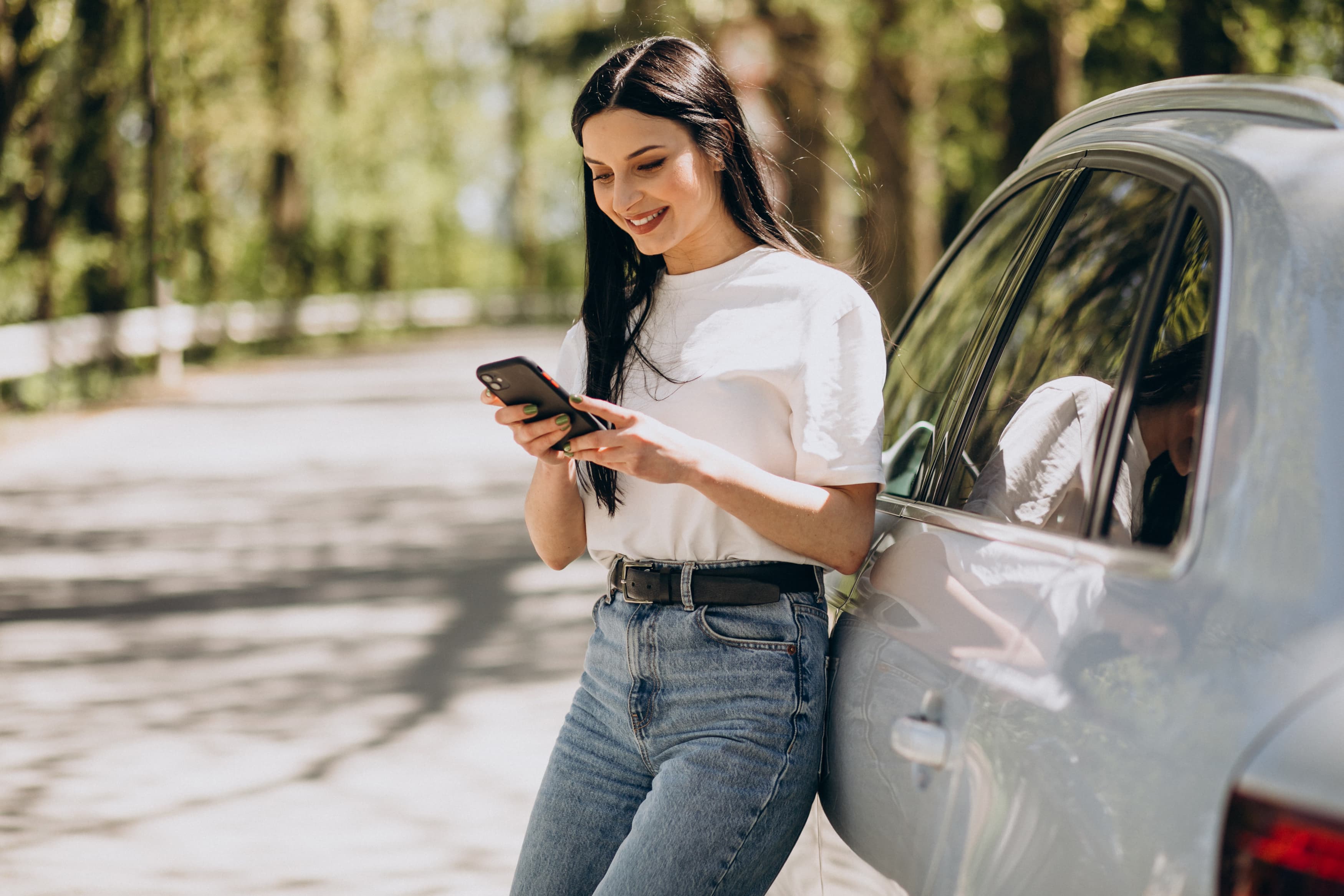 Frau sitzt in einem Auto und nutzt ihr Smartphone, um mit Autoeinfachlos eine Alternative zu „Wir kaufen dein Auto“ zu finden.