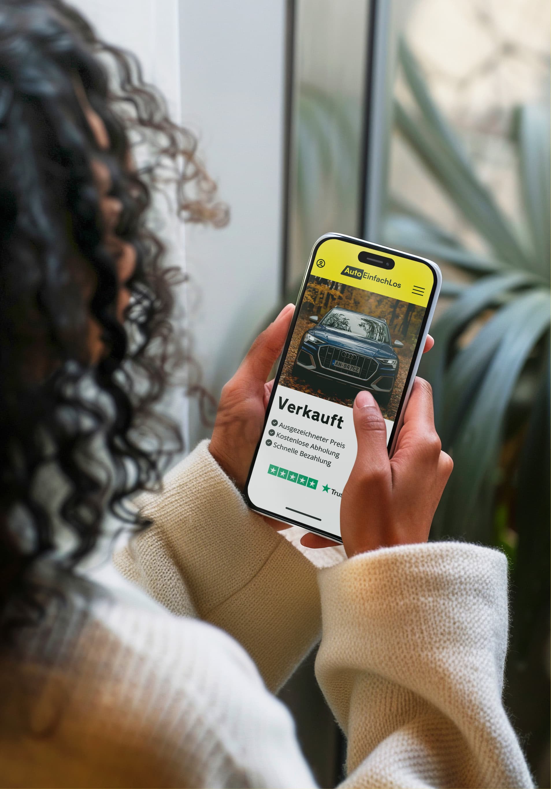 Frau lächelt und schaut auf ihr Smartphone, während sie den Höchstpreis für den Verkauf ihres Autos über Autoeinfachlos ermittelt