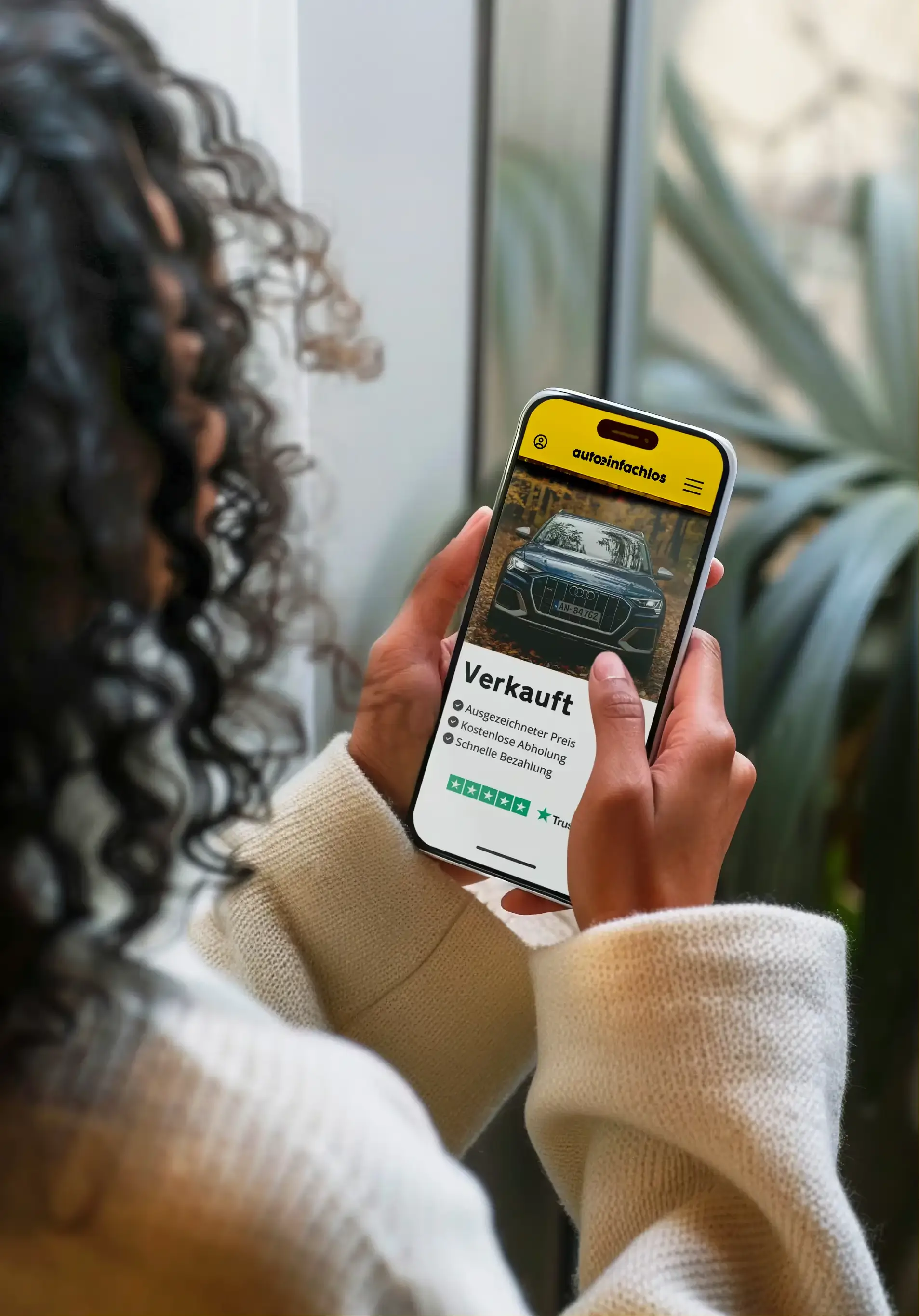 Frau sitzt in einem Auto und nutzt ihr Smartphone, um mit Autoeinfachlos eine Alternative zu „Wir kaufen dein Auto“ zu finden.